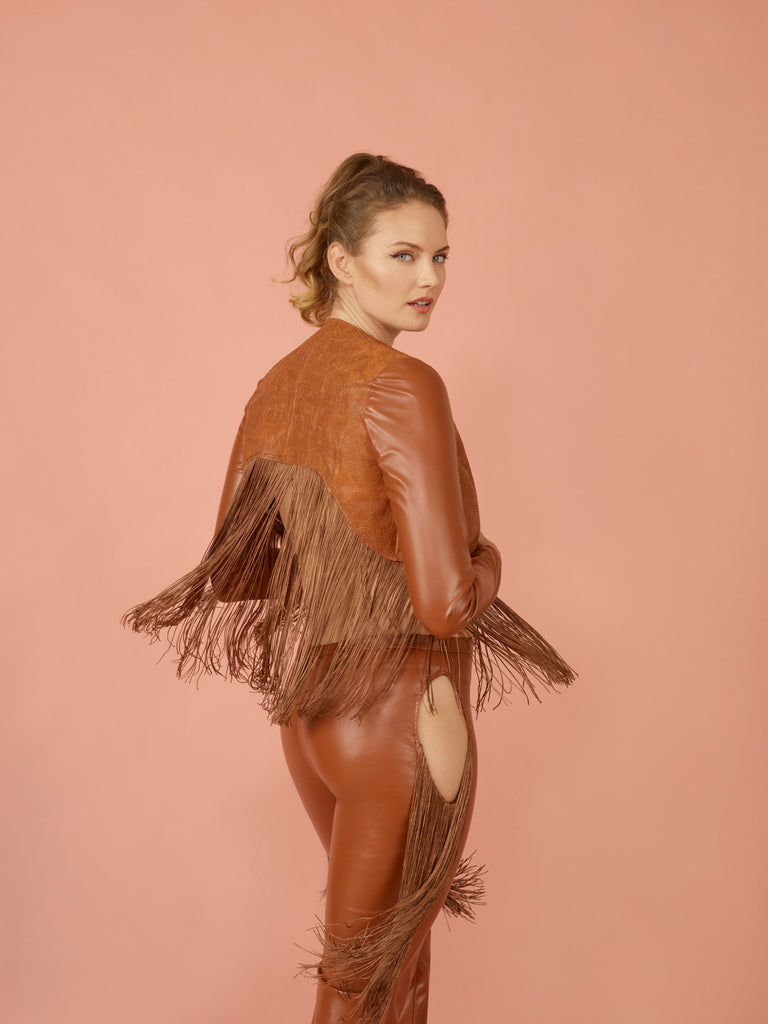 Back view of model wearing warm brown western cropped fringe jacket. Paired with matching brown pleather cut out jeans.