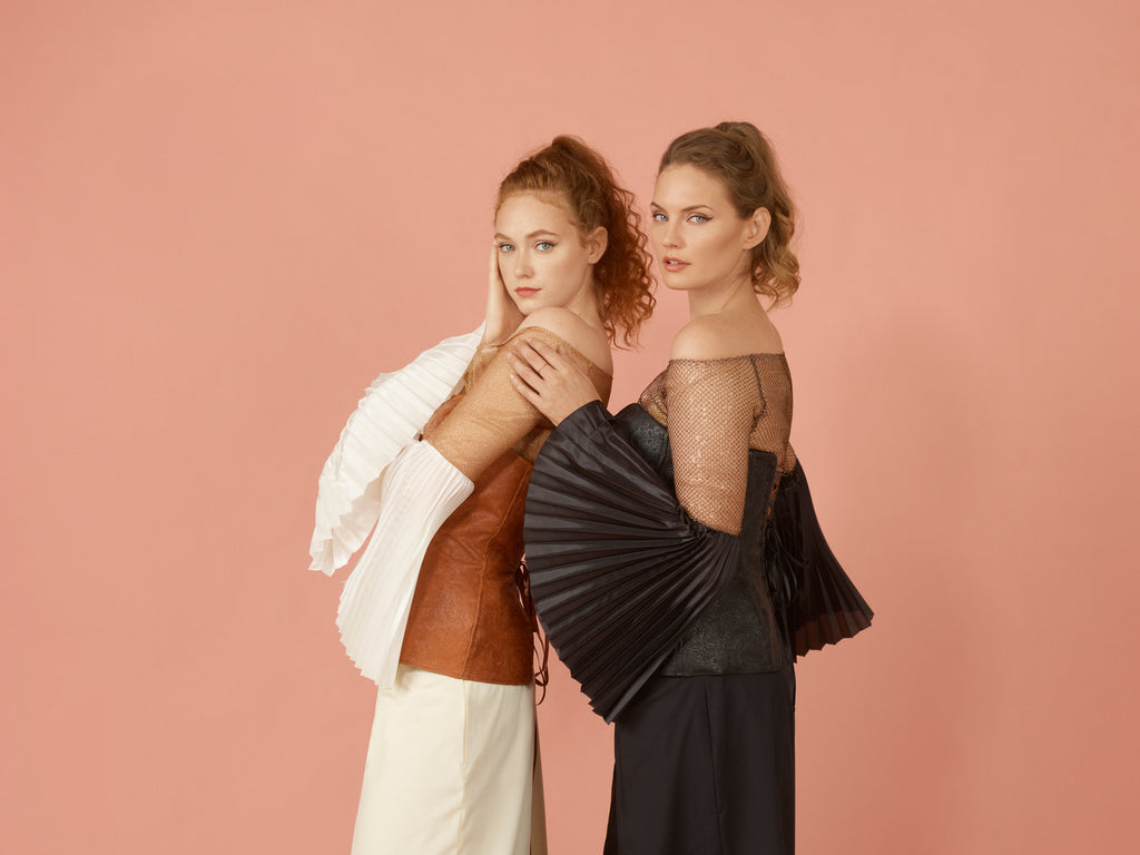 Picture of two models wearing metallic fishnet tops paired with corset layered on top. Side view of pleated silk sleeve in both black and white option.